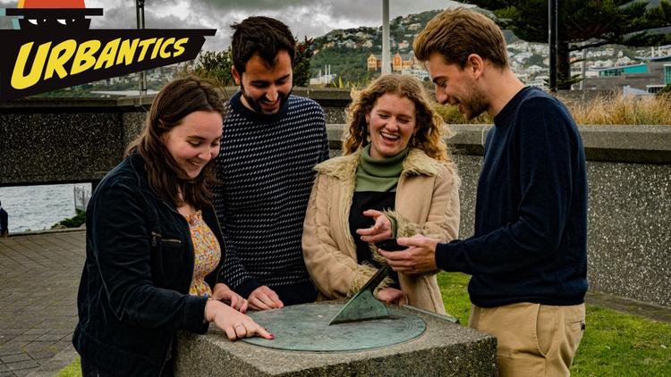 Four people pointing at a sundial