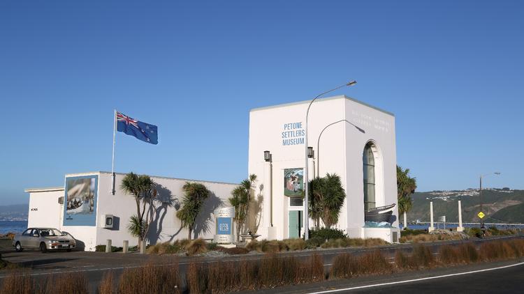 Photo of Petone Settlers Museum on a sunny day with the New Zealand flag flying in the wind.
